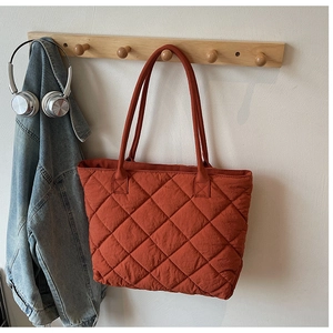 Gros plan d'un sac cabas matelassé orange avec motif à losanges sur un crochet mural