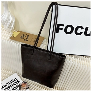 Detail view of deep brown faux leather tote bag with thin straps on a display stand