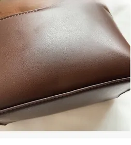 Close-up of dark brown leather bucket bag showing litchi texture and golden logo