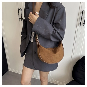 Braune Schultertasche aus Wildleder im Halbmond-Stil kombiniert mit einem grauen Blazer