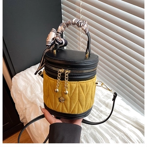 Detail einer gesteppten gelben Beuteltasche mit Goldakzent und bedrucktem Griffschal
