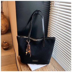 Detail of black vintage tote bag featuring striped lining and beaded decorative charm