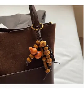 Detail of wooden bead bag charm with orange gourd pendant and gold metal ring