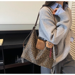 Détail du sac cabas léopard avec rabat en cuir brun et breloque ours sur modèle