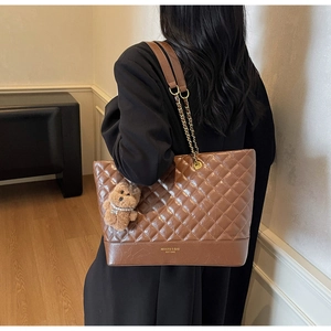 Détail du sac fourre-tout matelassé marron avec bandoulière chaîne et charm d'ours en peluche
