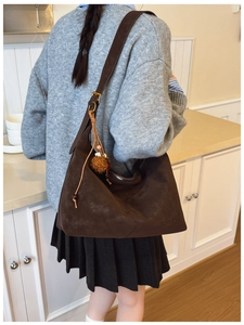 Detail of matte retro brown hobo bag featuring tassel and bead charms on shoulder strap