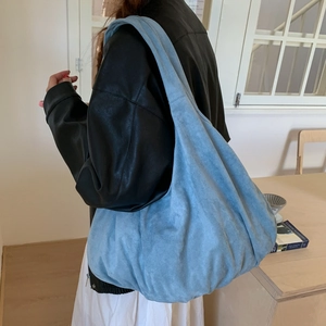 Model wearing a large light blue suede tote bag showing its soft texture and drape