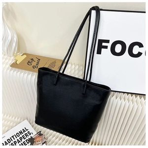 Minimalist black tote bag shown with slim straps and textured faux leather finish