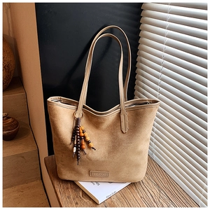 Detail of khaki suede tote bag with ethnic wooden beaded tassel and slim straps
