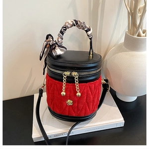 Detail der roten gesteppten Beuteltasche mit Goldblume und Seidentuch am Griff