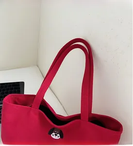 Detail of red canvas tote bag showing thick fabric texture and cute dog embroidery