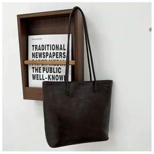 Close-up of vintage brown tote bag with oily wax leather texture and dual shoulder straps