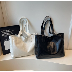 Close-up of pebble leather tote bags in cream and black with embossed logo detailing