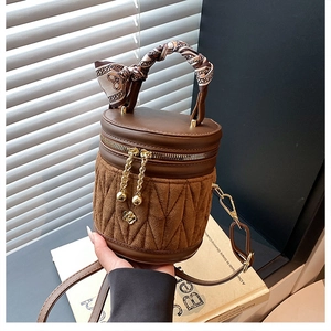 Nahaufnahme brauner Eimertasche mit geometrischer Steppung und Seidengriff-Details