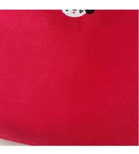 Detailed view of red canvas fabric with high-quality cartoon embroidery and woven texture