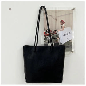 Macro detail of black leather tote bag featuring a matte texture and minimalist design
