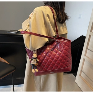 Detail of burgundy quilted tote bag with diamond stitching and rabbit charm