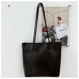 Detail of dark brown vintage faux leather tote bag with subtle wrinkled texture