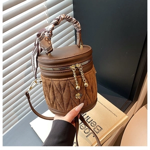 Detail einer braunen Stepp-Beuteltasche mit Kamelienschnalle und Seidenschal am Handgriff