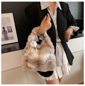 Detail view of plush beige faux fur tote bag with a whimsical monster puff charm accessory