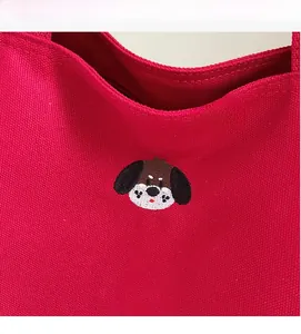 Close-up of pink canvas tote bag featuring detailed cartoon puppy embroidery and texture