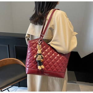 Detail of burgundy quilted leather tote bag with stylish plush rabbit charm accessory