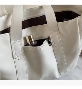 Detail of a beige faux leather tote showing a functional hidden zipper pocket on the back