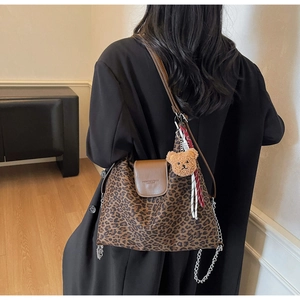 Détail du sac cabas léopard avec rabat en cuir marron et breloque d'ours en peluche