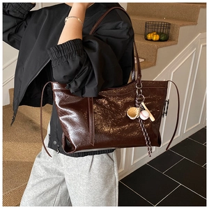 Détail du sac cabas marron foncé en cuir brillant avec pendentif créatif de baseball