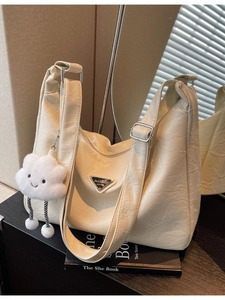 Beige pleated leather hobo tote with plush cloud charm and wide strap on minimalist books