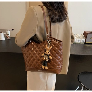 Detail view of brown quilted tote bag with retro diamond stitching and bunny charm accessory