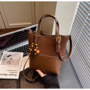 Detail of retro brown bucket bag featuring wood bead charm and premium leather texture