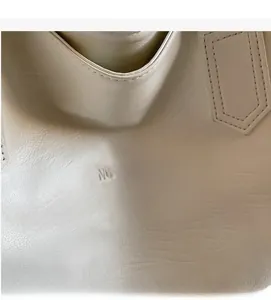 Close-up of creamy leather tote bag showing detailed stitching and NOCOBAG logo