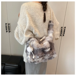 Détail du sac à bandoulière en peluche avec chaîne en métal et pompon décoratif
