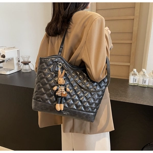 Close-up of black quilted tote bag with a cute plush bunny charm for daily commuting