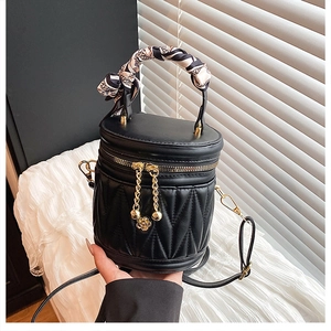 Details der schwarzen gesteppten Zylindertasche mit Blumengruß und Seidenschal-Griff