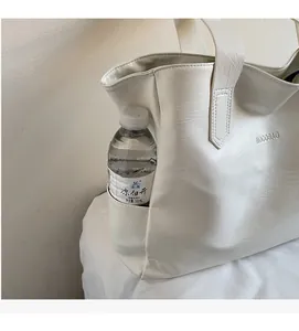 Detail view of large tote bag side pocket holding a water bottle with logo engraving