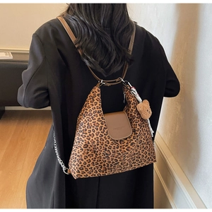 Détail du sac cabas léopard avec rabat en cuir, bandoulière chaîne et breloque ours en peluche