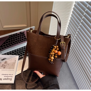 Détails du sac seau marron mat avec breloque en bois et bandoulière amovible
