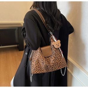 Détail du sac cabas léopard avec rabat en cuir marron, chaîne en métal et ours