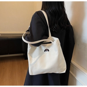 Detail of cute puppy embroidery on a white canvas tote bag with shoulder strap