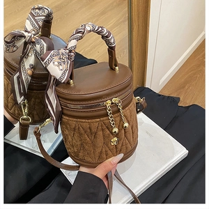 Detail einer braunen Eimertasche mit gestepptem Wildleder und Seidenschal-Griff
