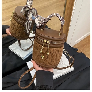 Detail der braunen Zylinder-Beuteltasche mit gestepptem Wildleder und Seidentuch-Griff