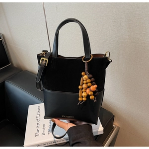 Detail of a black crossbody bag showing matte suede and smooth leather textures