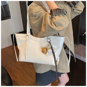 Gros plan d'un sac cabas blanc brillant avec détails de cordon et charms de baseball