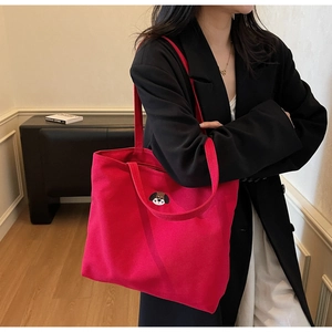 Detail of red canvas tote bag with cartoon dog embroidery and wide shoulder strap style