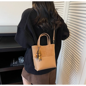 Détail du sac seau camel avec patchwork en daim et breloque en perles de bois sur modèle