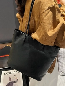 Minimalist black leather tote bag with large capacity shown in a stylish fashion setting