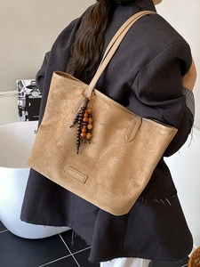 Retro khaki suede tote bag with wooden bead tassel shown on a stylish shoulder model