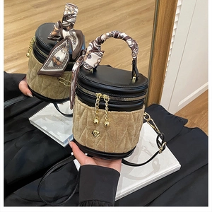 Detail der Samt-Eimertasche mit Kamelien-Anhänger und seidenem Schal am Griff